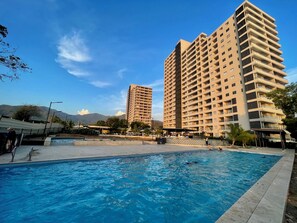 A swimming pool with a view of tall residential buildings and mountains in the background. - Santa Marina Sierra & Caribbean Retreat (Santa Marta)
