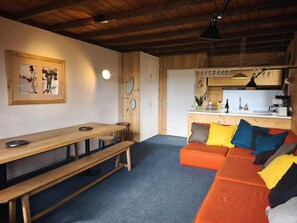 A cozy room with a wooden bench, a sofa with colorful cushions, a kitchen area, and a framed picture on the wall. - Up to 300 meters from the gondola lifts, balcony, TV, ski locker, 55 m², Pra Loup (Pra Loup)