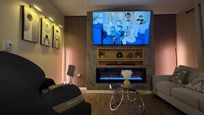 A living room with a flat-screen TV, a massage chair, a sofa, and a fireplace. - Spacious Luxury 3BR by Lake & Park in Roselle (Roselle)