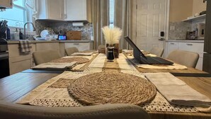 A dining area with a long table, multiple placemats, and a laptop on the table. - Spacious Luxury 3BR by Lake & Park in Roselle (Roselle)