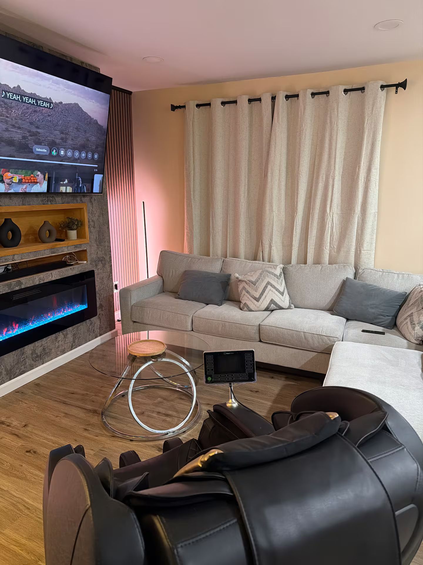 Ett modernt vardagsrum med en platt-TV, en soffa, ett soffbord och en massagefåtölj.