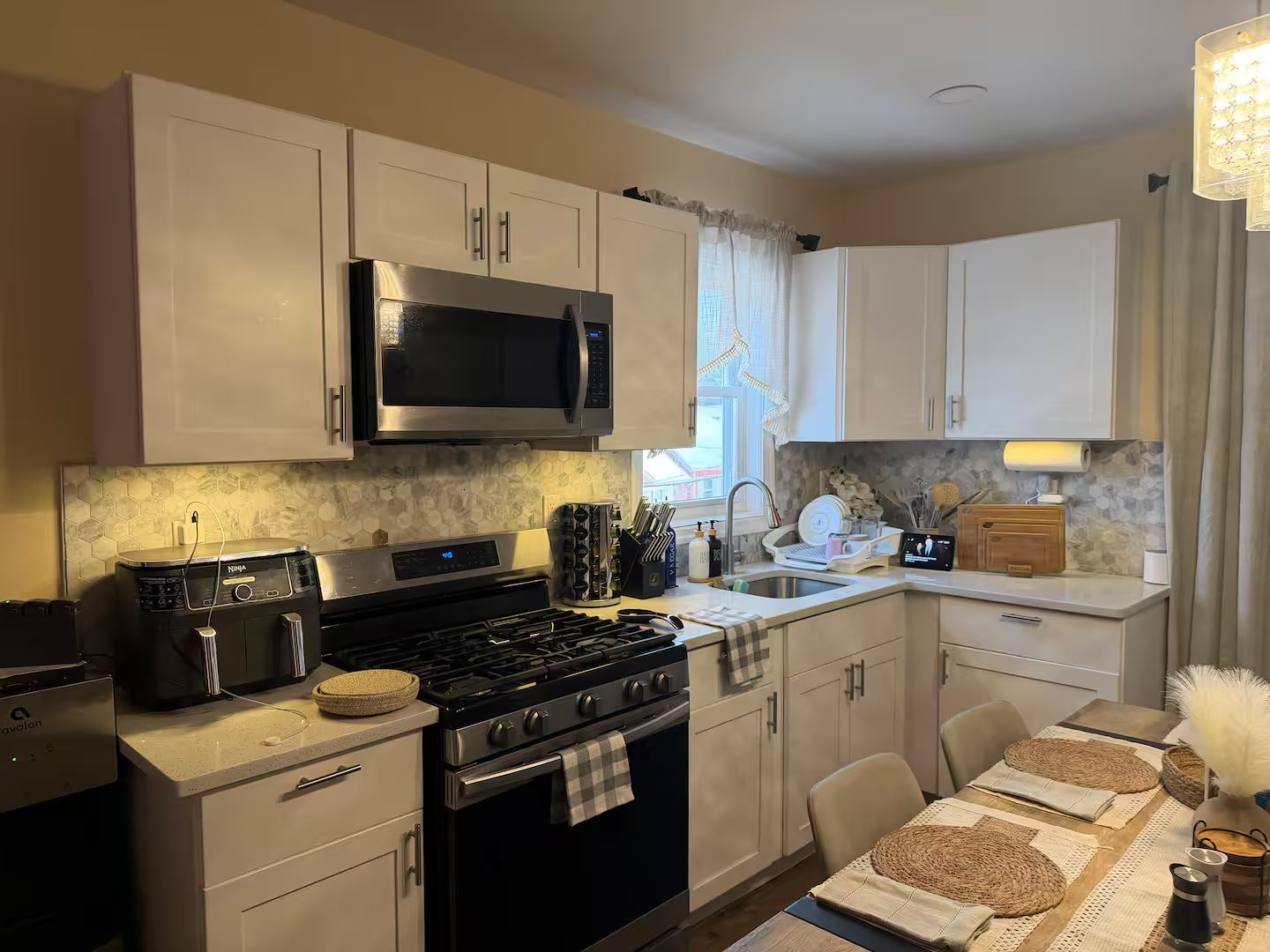 A modern kitchen with a stove, microwave, and sink. There is a dining area with a table and chairs.