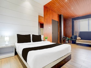 A modern bedroom with a large bed, a nightstand, a bedside lamp, a wooden ceiling, and a view of the outside. - Collection O Jaigaon Near Bhutan Gate (Alipurduar)