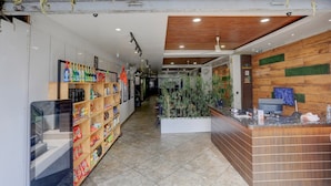 A reception area with a wooden reception desk, a counter with a computer, and shelves with various items. - Collection O Jaigaon Near Bhutan Gate (Alipurduar)