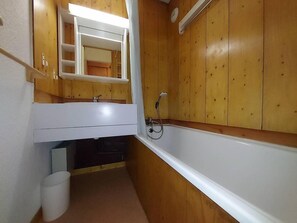 A bathroom with wooden walls, a white bathtub, and a mirror above the sink. - 10m from ski slopes, Ground floor, terrace, tv, ski locker, 27m², Valmorel (Valmorel)