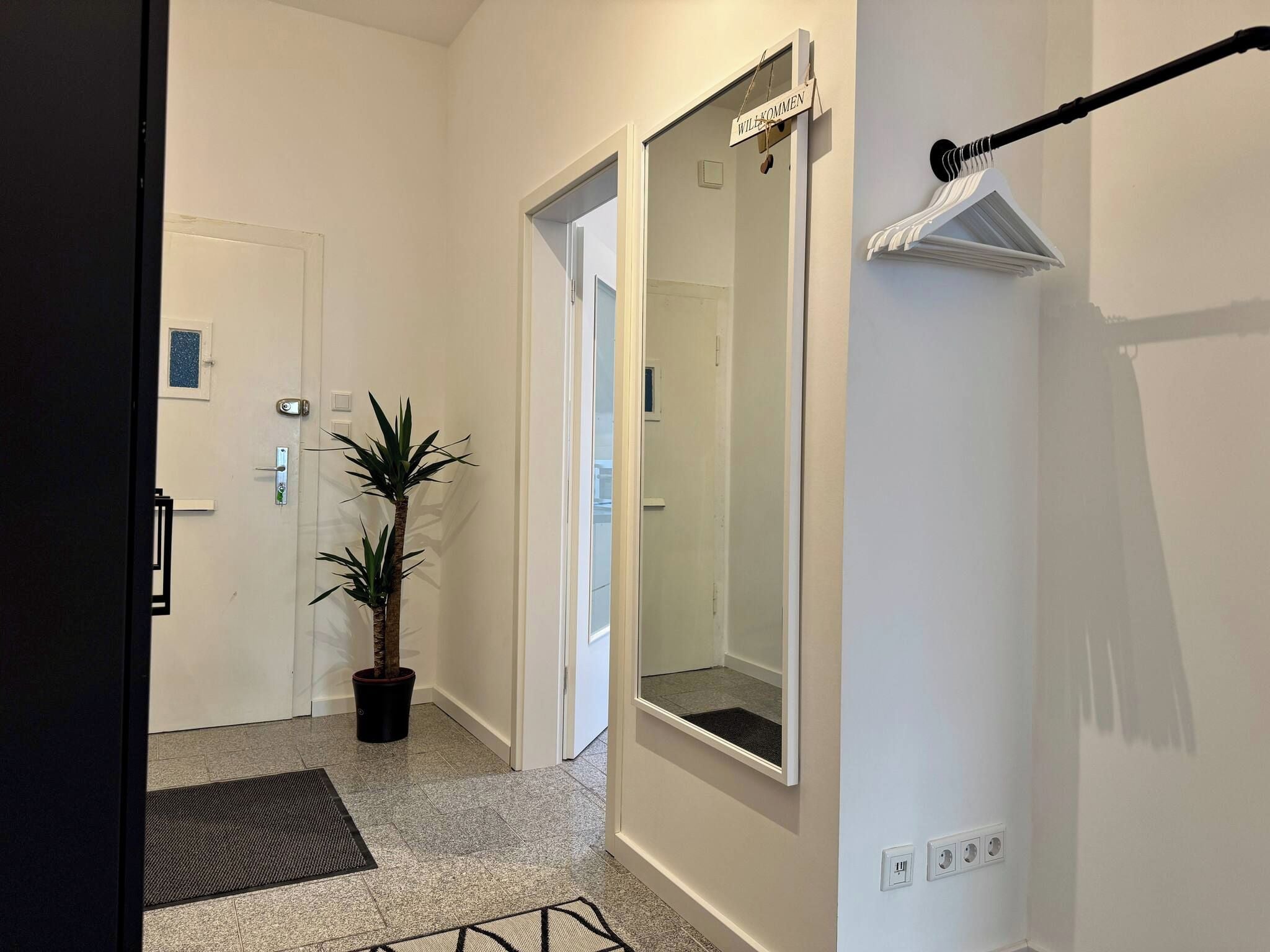A hallway with a potted plant, a door with a sign, and a towel rack.
