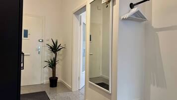 A hallway with a potted plant, a door with a sign, and a towel rack.