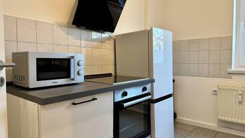 Une cuisine compacte équipée d’un four à micro-ondes, d’un four et d’un réfrigérateur.