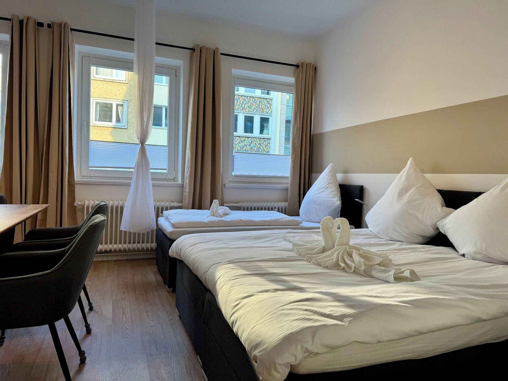 A hotel room with two beds, a desk, and a chair.