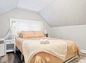 Un dormitorio con cama, mesita de noche, lámpara y ventana con persianas.