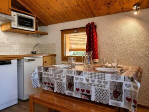 A kitchen with a table set for two, a microwave, and a window with curtains. - 100m from ski slopes, floor -1, balcony, tv, ski locker, 24m², Méribel-Mottaret (Les Allues)