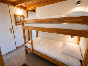 A bunk bed with a wooden frame and white bedding. - 100m from ski slopes, floor -1, balcony, tv, ski locker, 24m², Méribel-Mottaret (Les Allues)