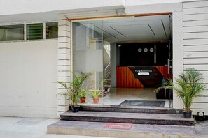 A building entrance with a glass door, steps, and potted plants. - Super Townhouse Marathahalli (Bengaluru)