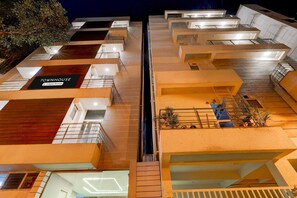 A multi-story building with a modern architectural design, featuring a central staircase, balconies, and a sign that reads 'TOWNHOUSE & Company Services.' - Super Townhouse Marathahalli (Bengaluru)