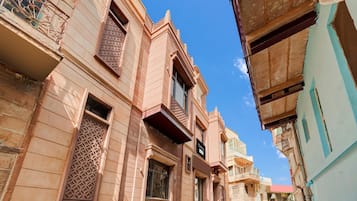 A narrow street with traditional architecture, including balconies and decorative window grills.