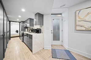 A modern kitchen with a central island, a microwave, and a coffee maker. - Cozy Little Portugal 2BR | Sleeps 6 (Toronto)