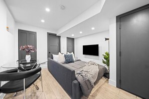 Ein modernes Schlafzimmer mit Schlafsofa, Glastisch und Fernseher.