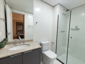 Un baño moderno con encimera de granito, inodoro y ducha con mampara de vidrio.