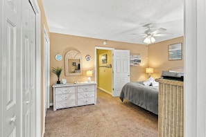 Wicker furniture and sand-colored walls create a tranquil coastal mood in this spacious bedroom. Glowing lamps cast a gentle radiance over the plush carpet and crisp linens, offering a quiet space to rest after a long day by the sea. - Renovated Shipyard Villa, Bike to the Beach! (Hilton Head Island)