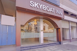 A hotel named Skyboat Inn with a modern facade, large glass windows, and a prominent arched entrance.