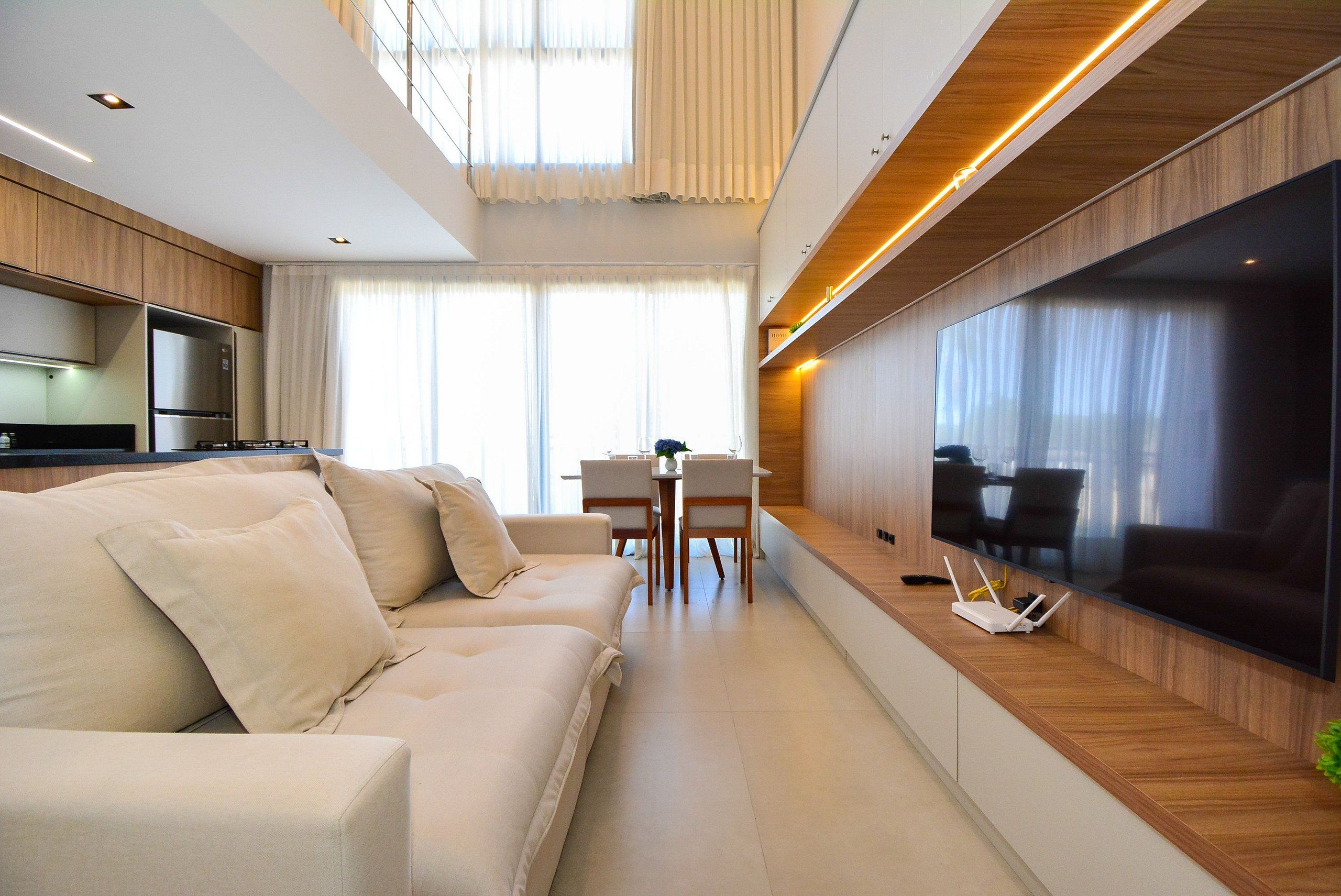 Una sala de estar moderna con un sofá, una mesa de comedor y un televisor de pantalla plana montado en la pared.