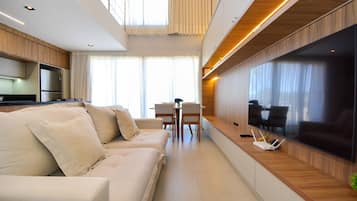 Una sala de estar moderna con un sofá, una mesa de comedor y un televisor de pantalla plana montado en la pared.