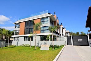 A modern multi-story building with a sign reading "Sunset Lagoon." - Elegante Loft Sunset Lagoa - LDI006 (Florianópolis)