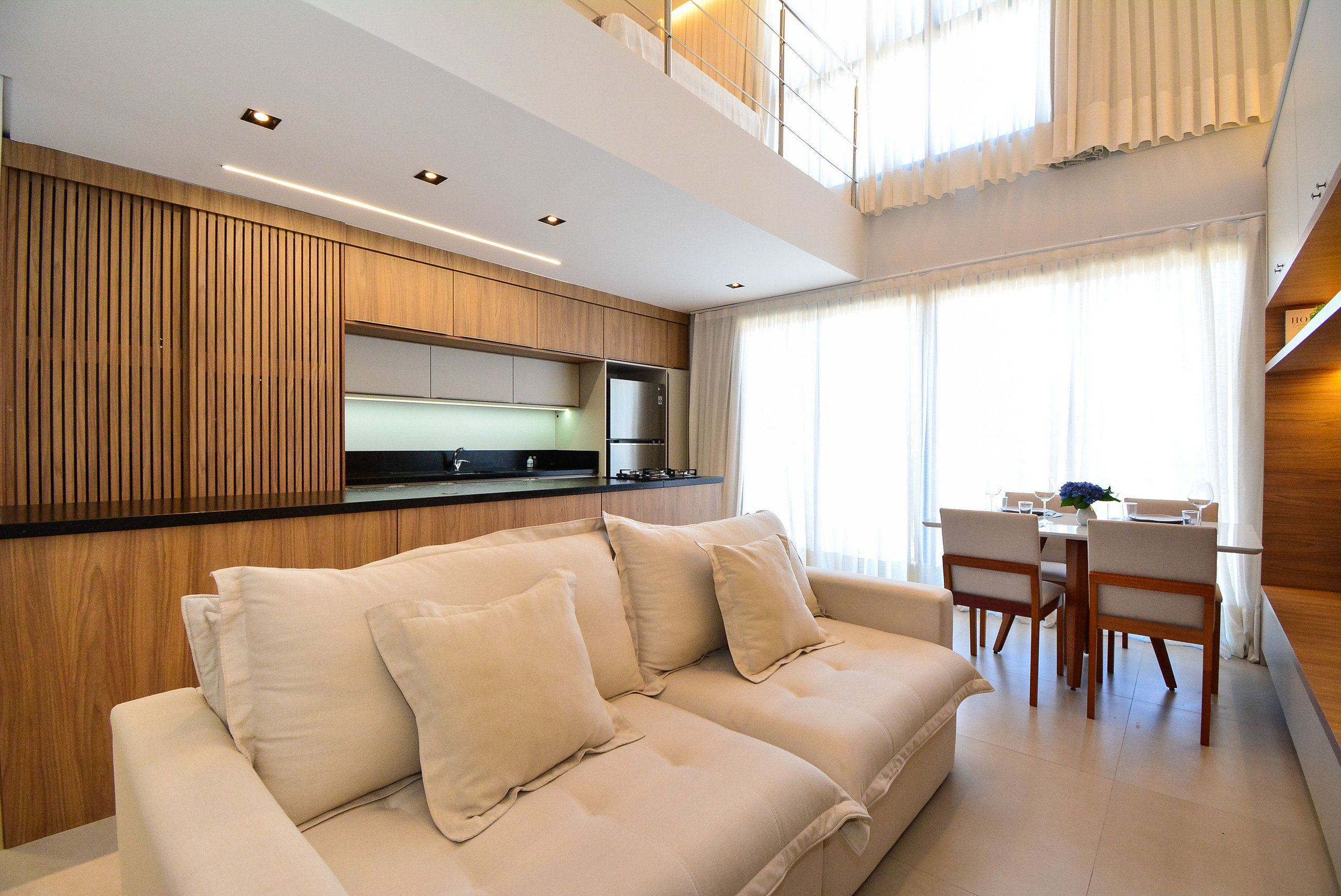Una sala de estar moderna con sofá, mesa de comedor y zona de cocina.