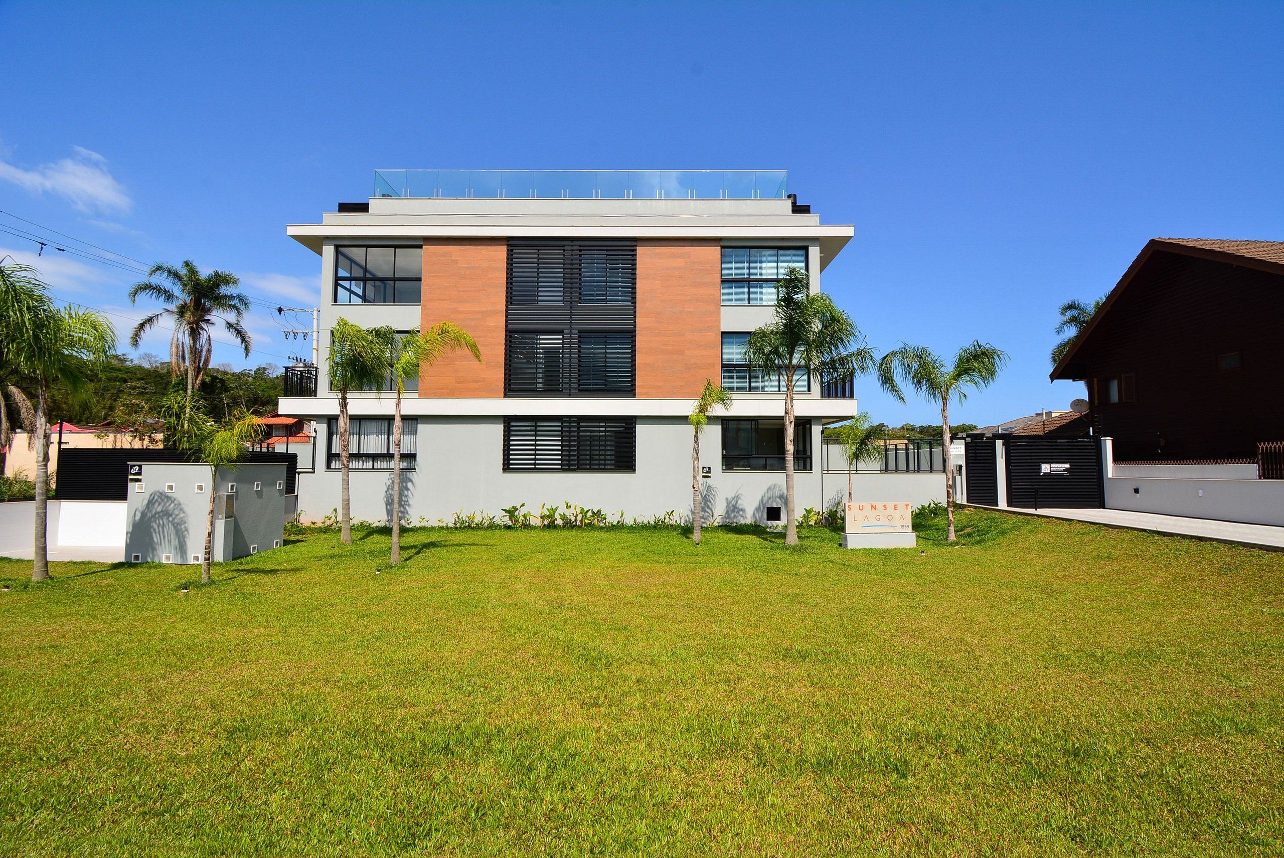 Un edificio moderno de dos pisos con techo plano, ventanas amplias y un letrero que dice "Sunset Villa".