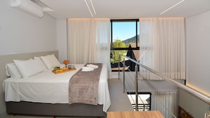 Une chambre à coucher avec un lit, une table de chevet avec un plateau, une fenêtre avec des rideaux et un balcon avec une balustrade.