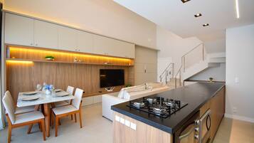 Una cocina moderna con comedor, electrodomésticos integrados y una escalera.