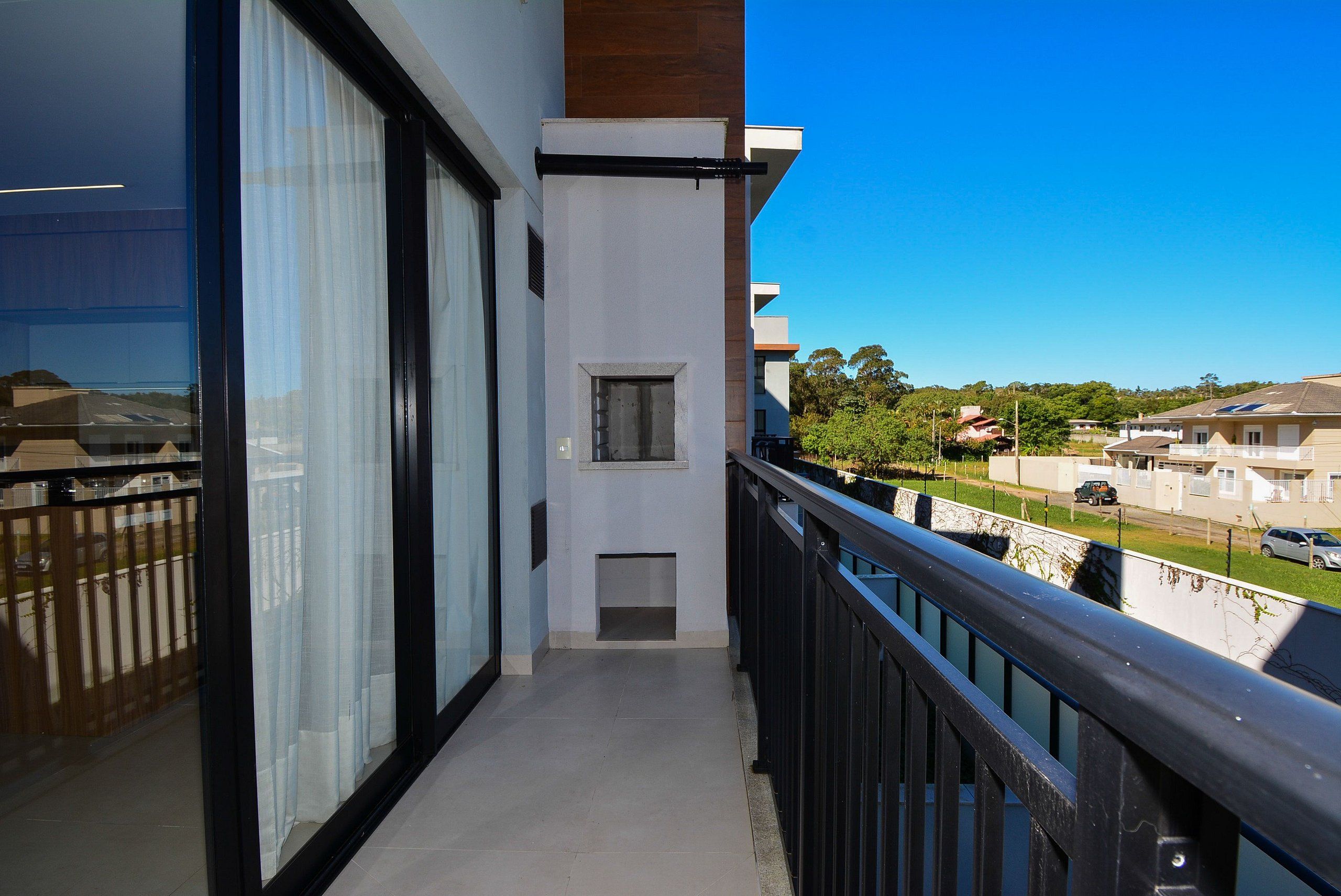 A balcony with a view of a residential area, a small window, and a door.