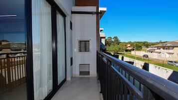 A balcony with a view of a residential area, a small window, and a door.