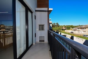 Un balcón con vista a un barrio residencial, una ventana pequeña y una puerta.