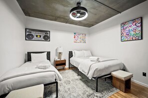 Ein modernes Schlafzimmer mit zwei Betten, einer Deckenleuchte und Bildern an den Wänden.