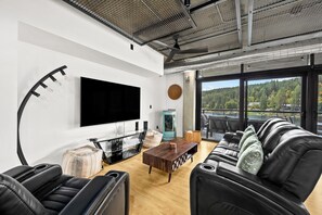 Ein modernes Wohnzimmer mit großem Flachbildfernseher, Ledersofas, einem Holztisch und einem dekorativen Steinkunstwerk.