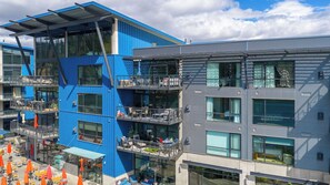 Un immeuble à plusieurs étages doté de balcons, de grandes fenêtres et d’espaces extérieurs aménagés pour s’asseoir.