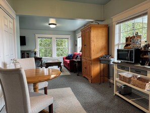 A compact kitchen with a dining table, a red sofa, and a large wooden cabinet.