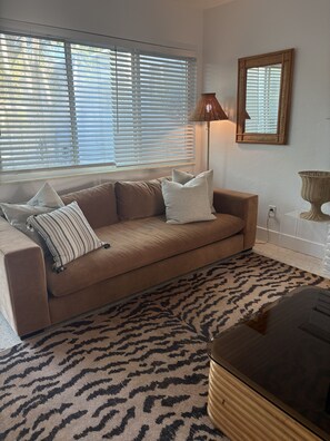 A living room with a beige sofa, patterned rug, and a lamp. - Mid-Century with Outdoor Oasis (Fort Lauderdale)