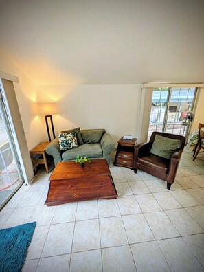 A living room with a sofa, a coffee table, a chair, a lamp, and a window.