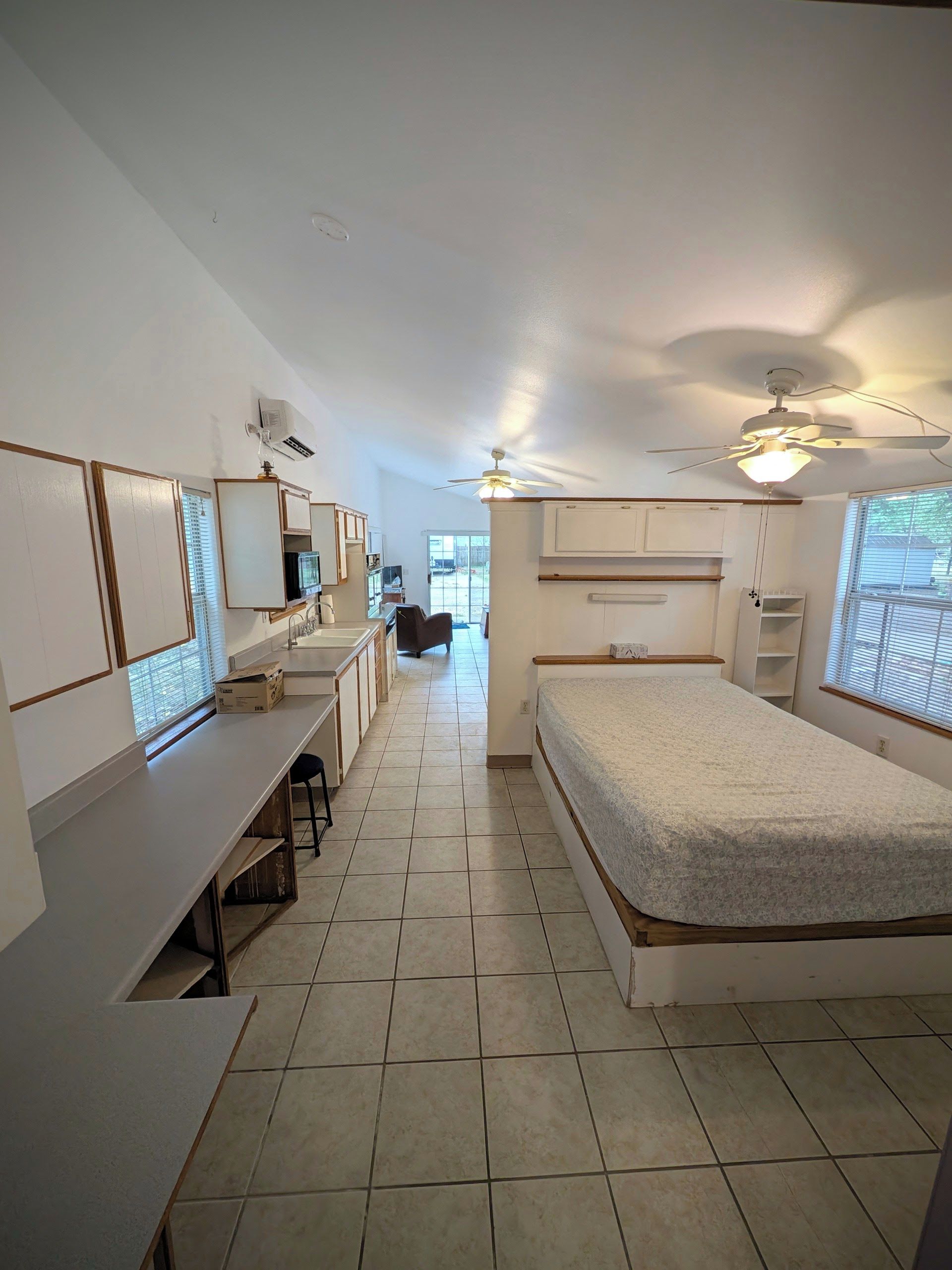A bedroom with a bed, a desk, a chair, and a window.