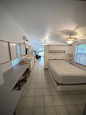 A bedroom with a bed, a desk, a chair, and a window.