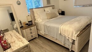 A bedroom with a bed, a dresser, a mirror, and a window. - Bright, Cozy Home Close to Everything. (Fort Lauderdale)