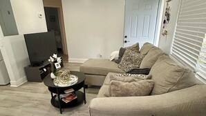 A living room with a sofa, a coffee table, and a television. - Bright, Cozy Home Close to Everything. (Fort Lauderdale)