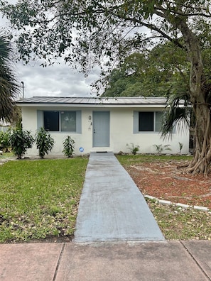A single-story house with a front door, windows, and a paved driveway leading to the entrance. - Bright, Cozy Home Close to Everything. (Fort Lauderdale)
