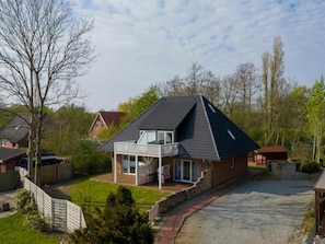 A two-story house with a balcony, a driveway, and a fenced yard. - 1 "coastal Child" (St. Peter-Ording)