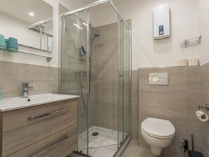 A modern bathroom with a glass-enclosed shower, a toilet, and a vanity with a sink. - 1 "coastal Child" (St. Peter-Ording)