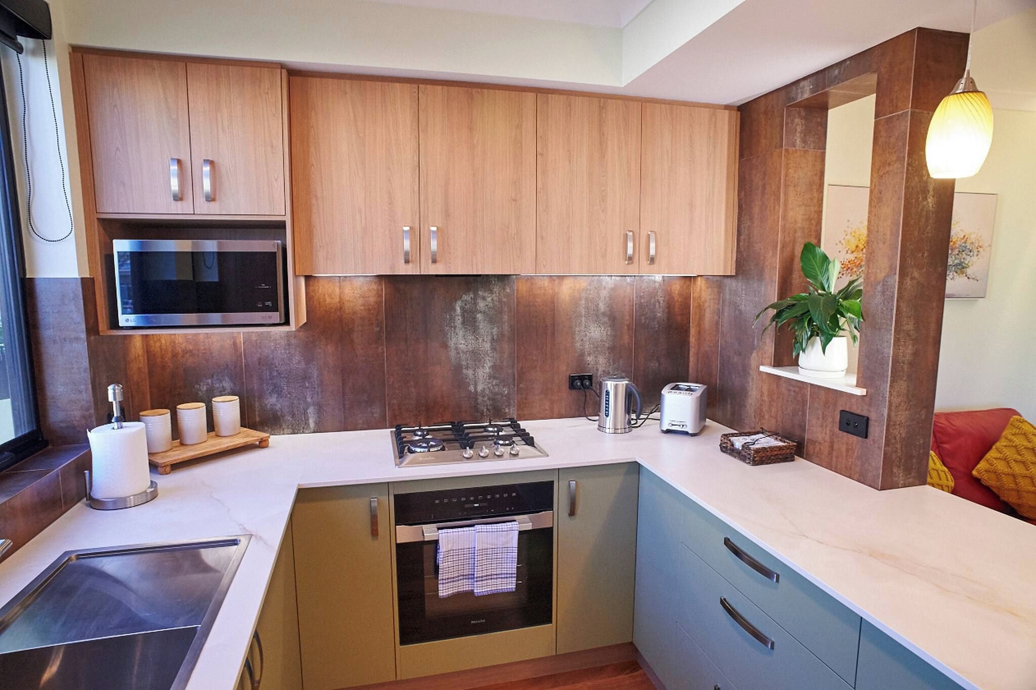 Una cocina moderna con armarios de madera, microondas integrado, estufa a gas y lavavajillas.