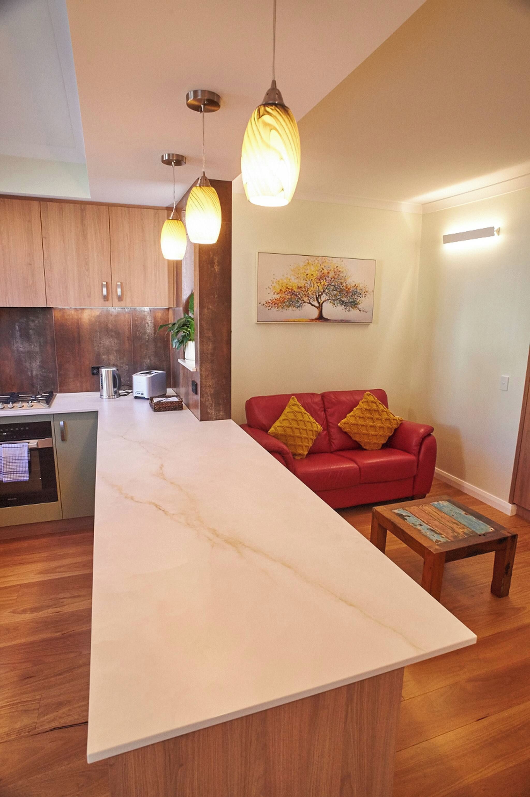 A modern kitchen with a central island, wooden cabinets, and pendant lighting.