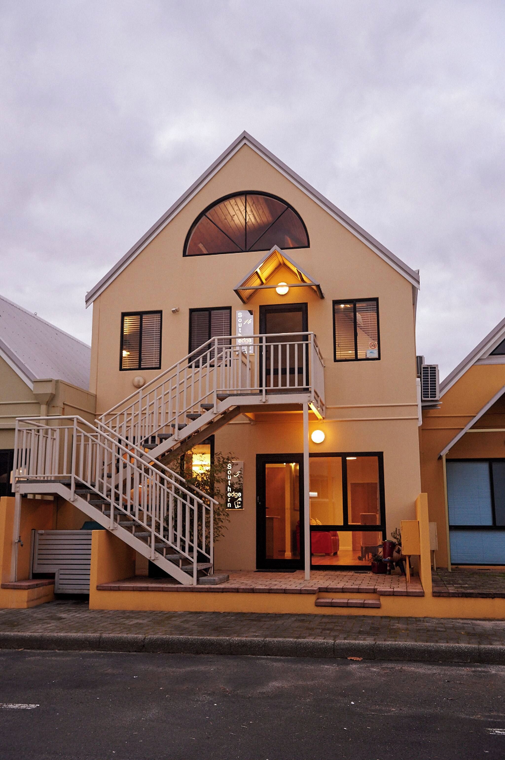 A two-story building with a balcony, a staircase, and a large window.